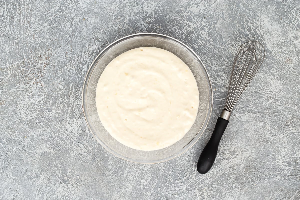Pancake batter in a bowl with a whisk next to it.