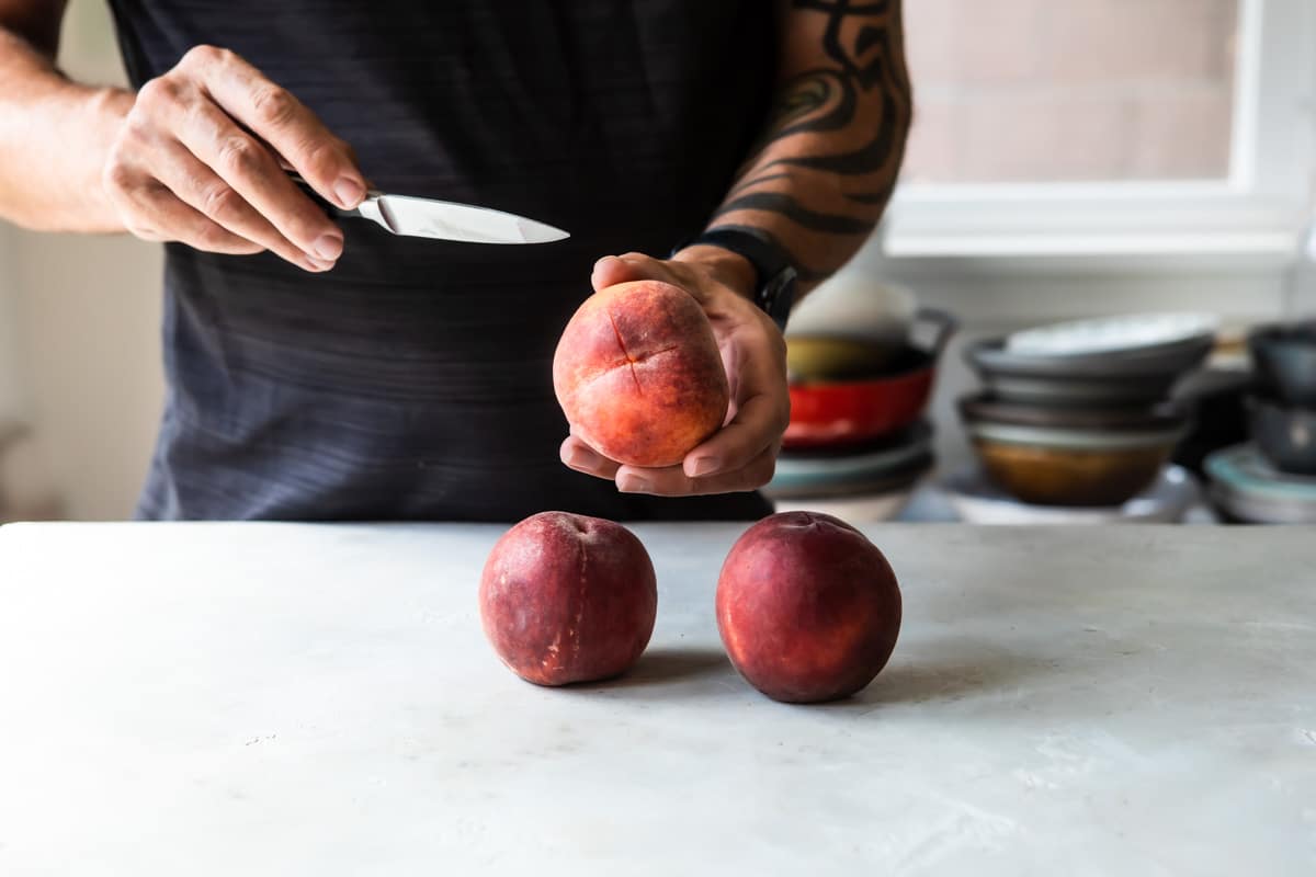 Someone marking an x on a peach.