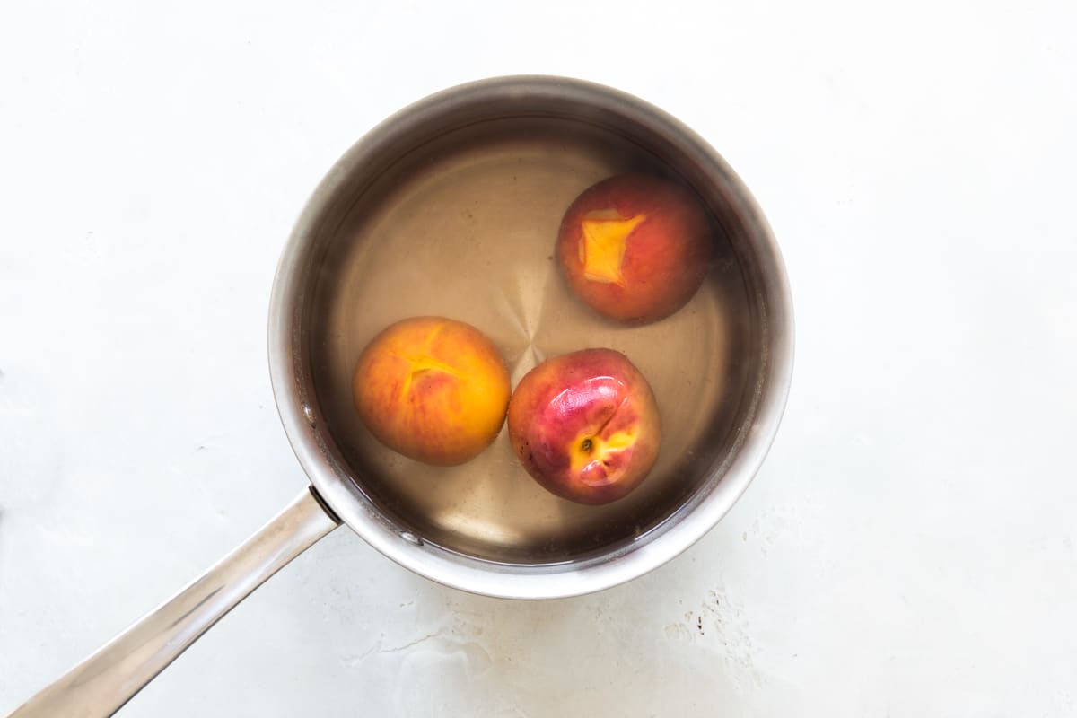 Peaches in hot water for peeling.
