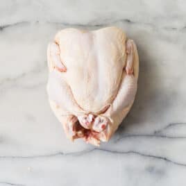 Someone trussing a raw chicken.