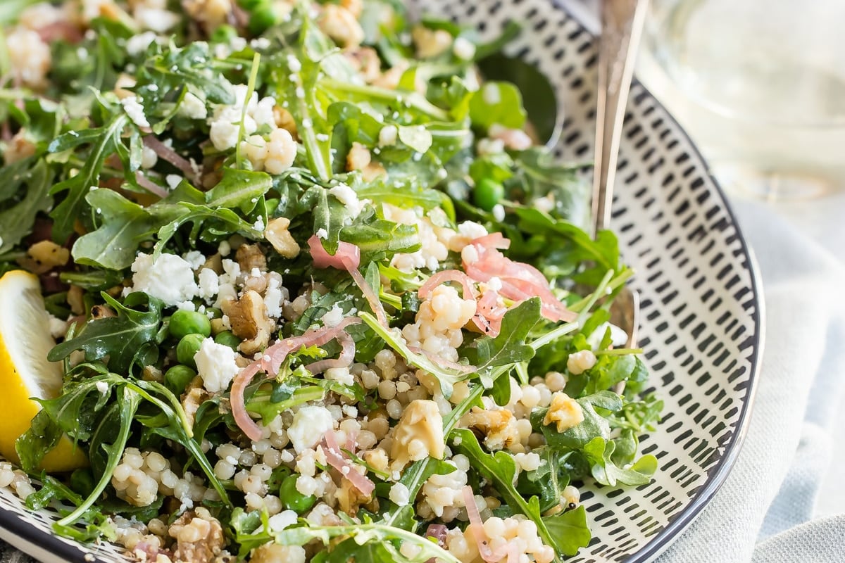 Israeli Couscous salad on a white and black platter.