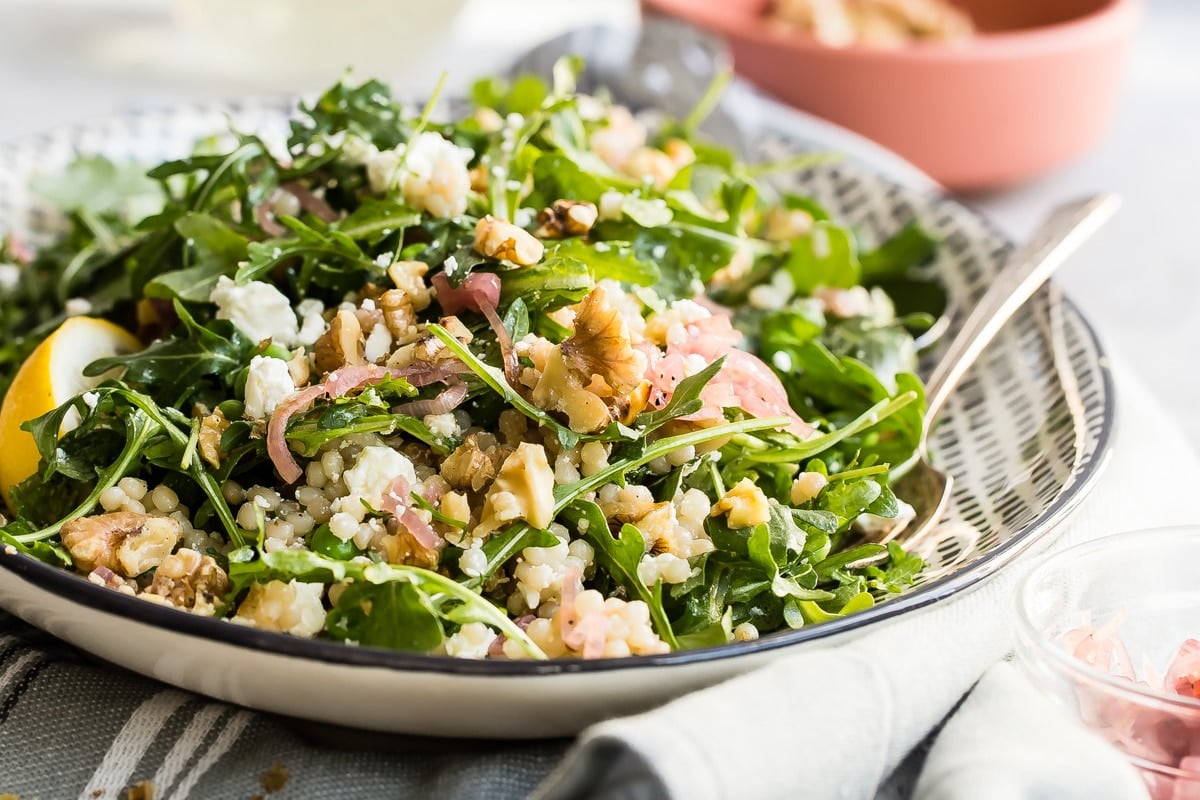Israeli Couscous salad on a white and black platter.