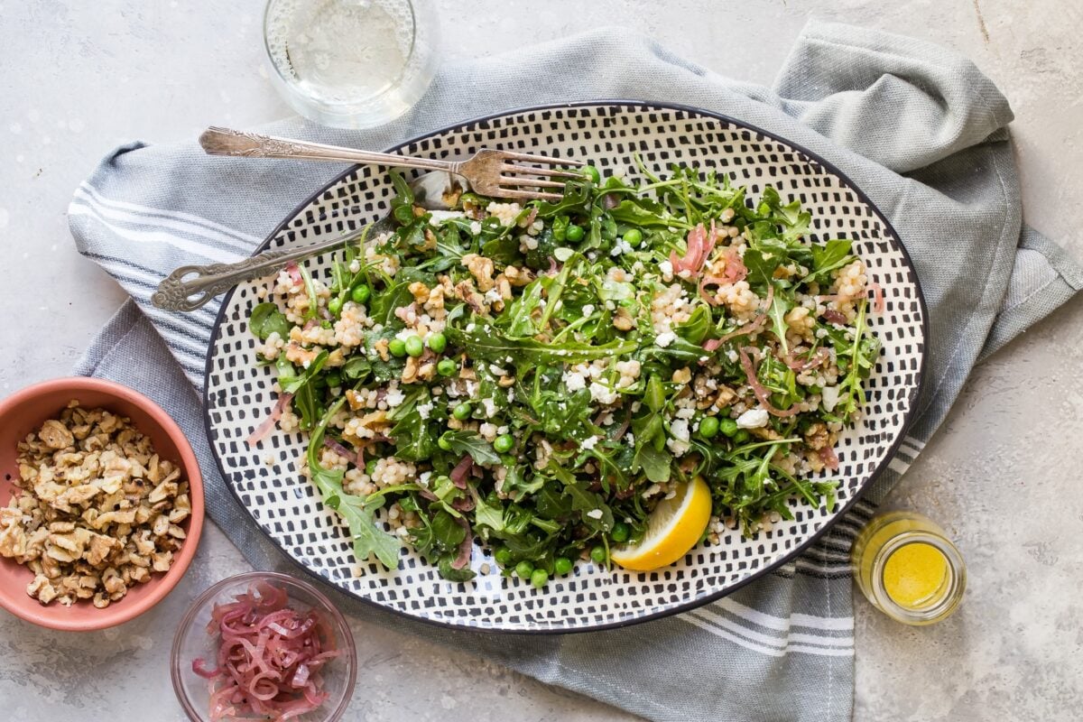Israeli Couscous salad on a white and black platter.