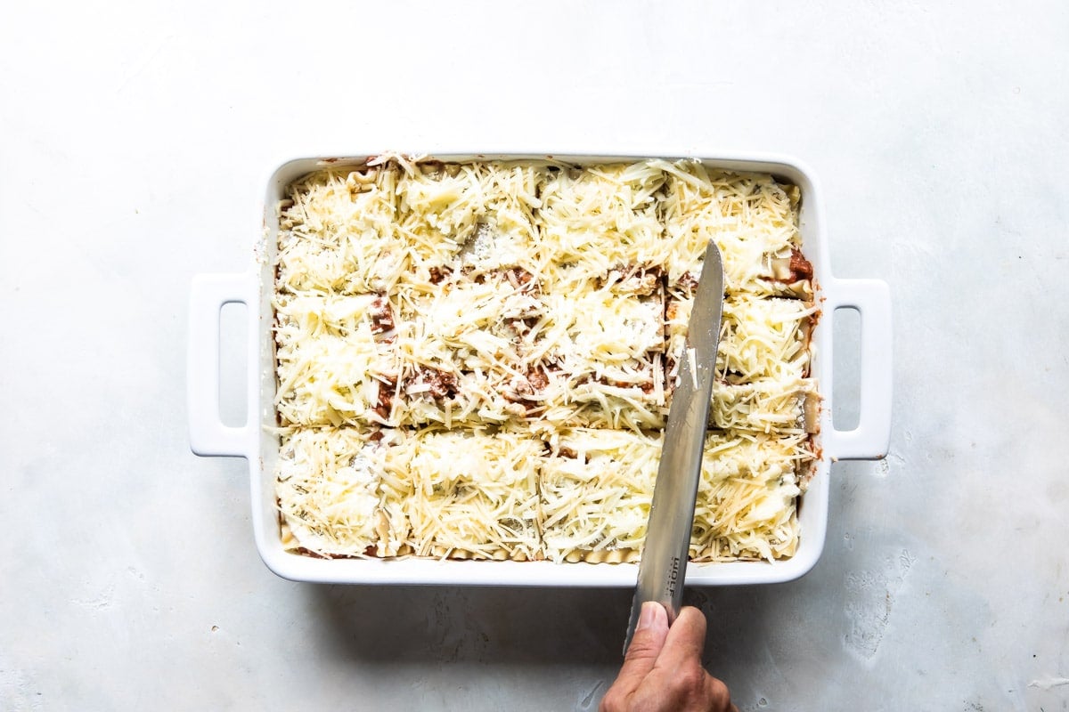 Slicing an unbaked lasagna before baking.