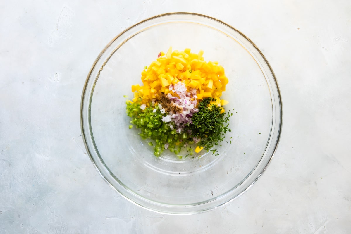 Ingredients for mango salsa in a clear bowl.