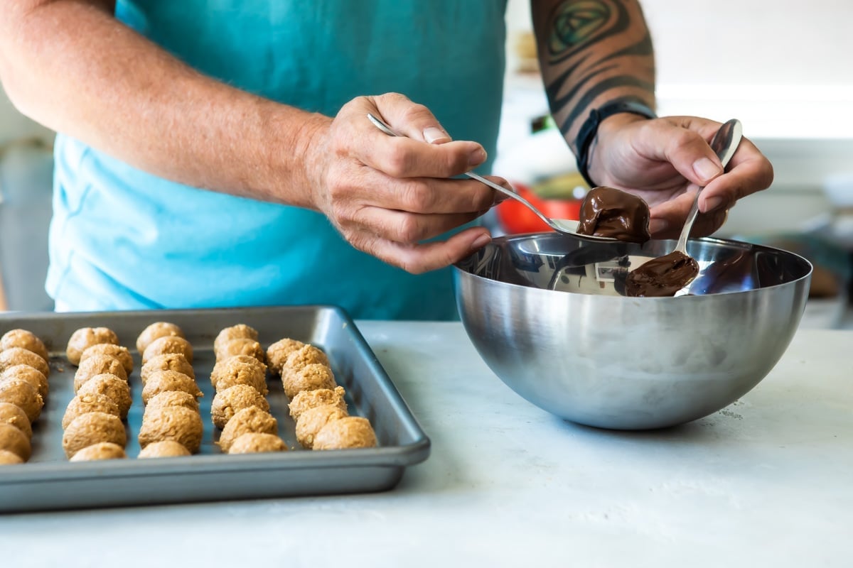 Someone dipping balls of peanut butter into chocolate.