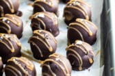 Oreo cookie balls on a parchment paper lined baking sheet.