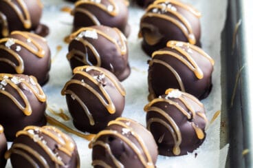 Oreo cookie balls on a parchment paper lined baking sheet.