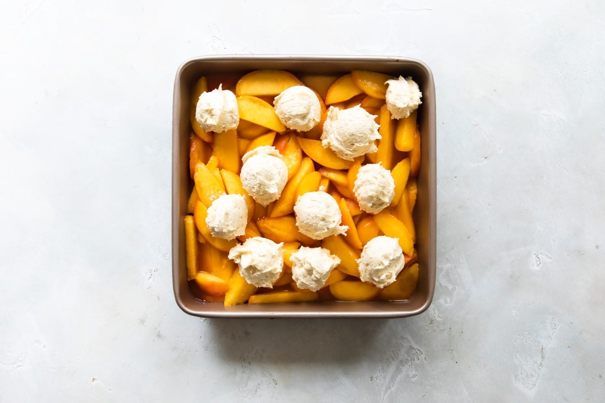 Unbaked peach cobbler in a baking dish.