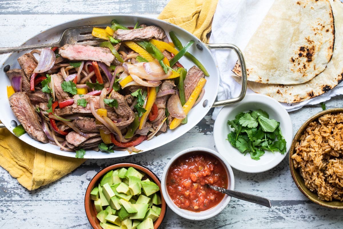 Steak fajitas in a white serving dish.