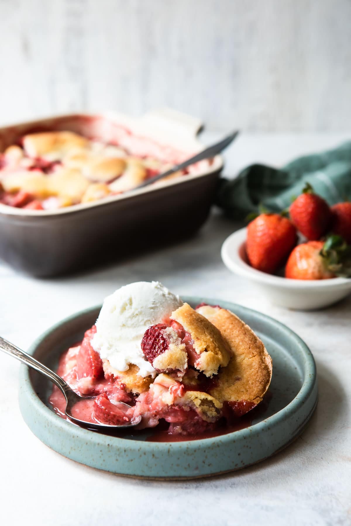 A dish of strawberry cobbler with ice cream.