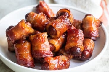 Bacon wrapped smokies in a white bowl.