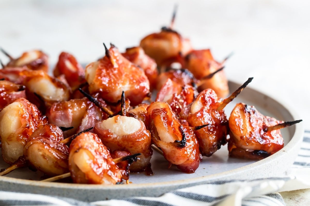 Bacon wrapped water chestnuts on a gray plate.