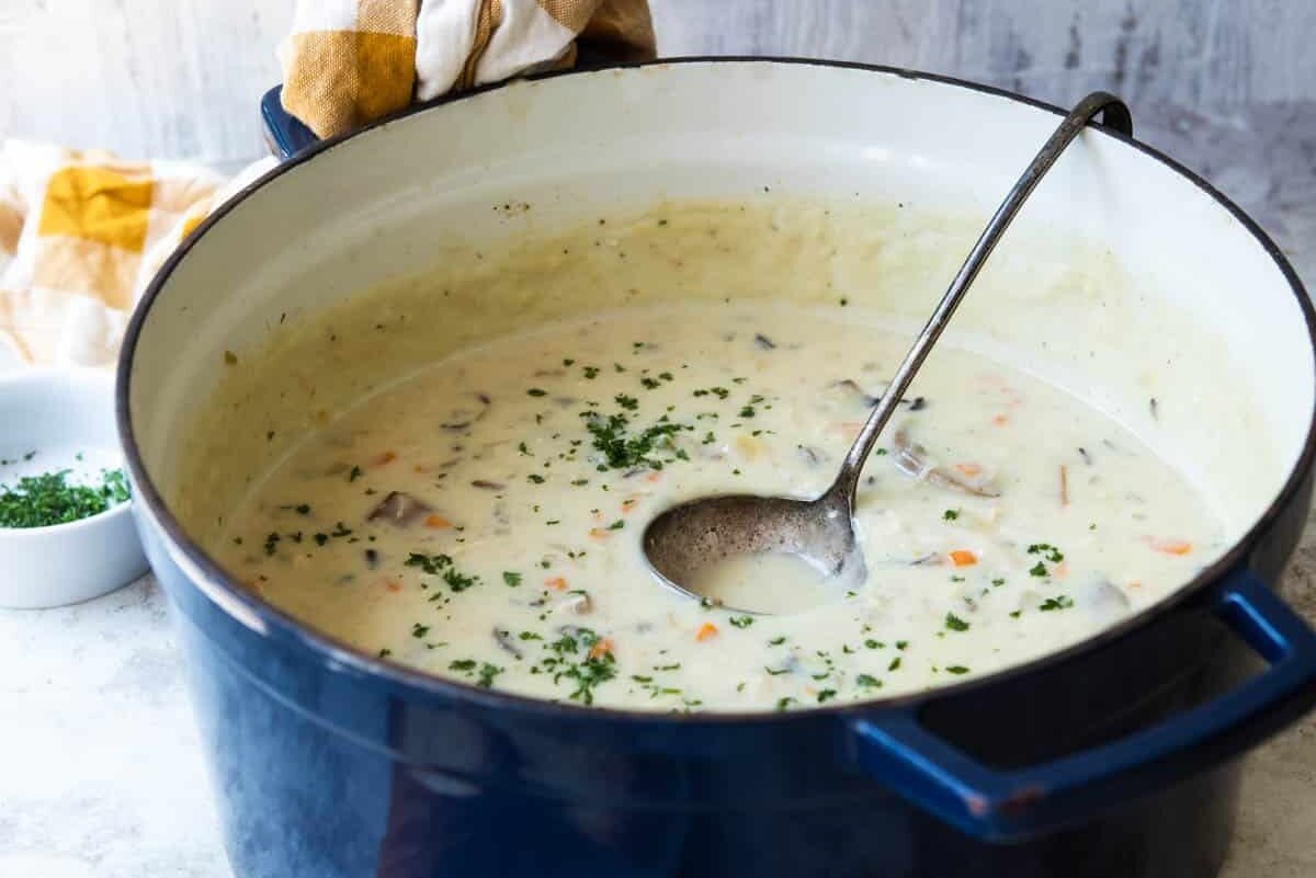 Chicken wild rice soup in a Dutch oven with a ladle.