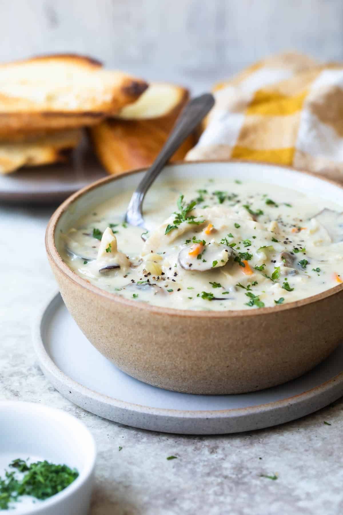 A brown bowl with chicken and wild rice soup.
