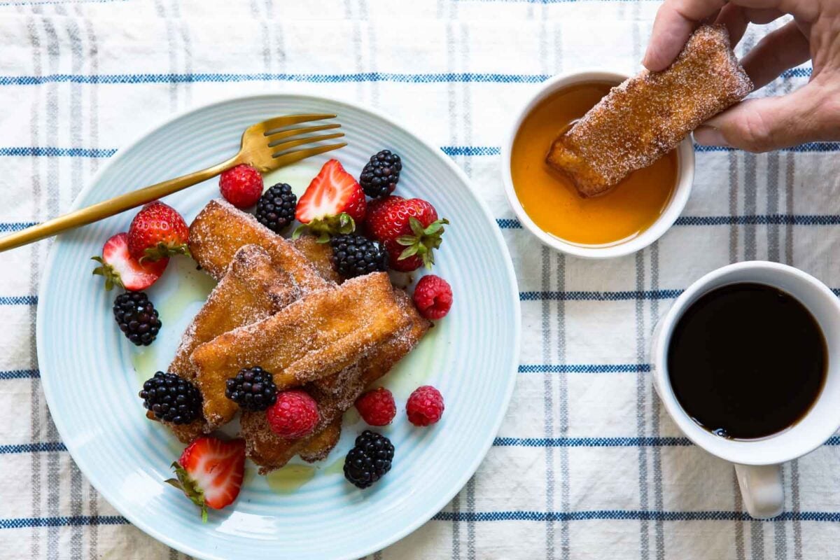 A stack of French toast sticks covered in berries on a plate.