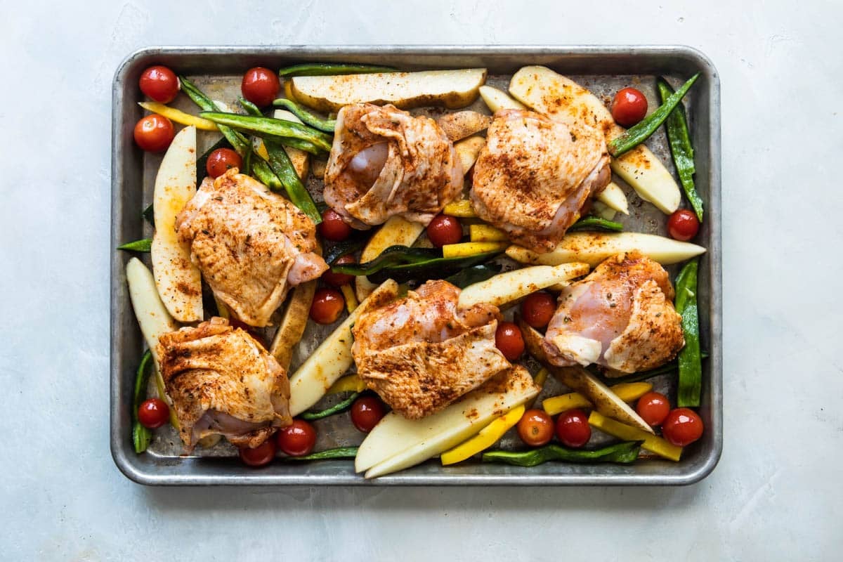 Paprika chicken and vegetables on a baking sheet before being cooked.