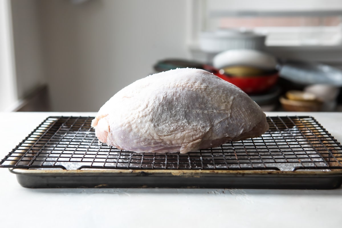 A raw turkey breast on a rack.
