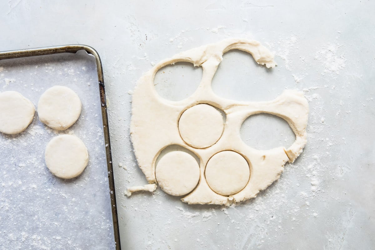 Biscuits being cut out of dough and placed onto a baking sheet.