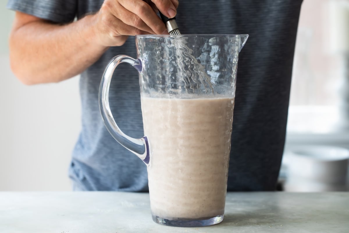 Stirring horchata in a glass pitcher.