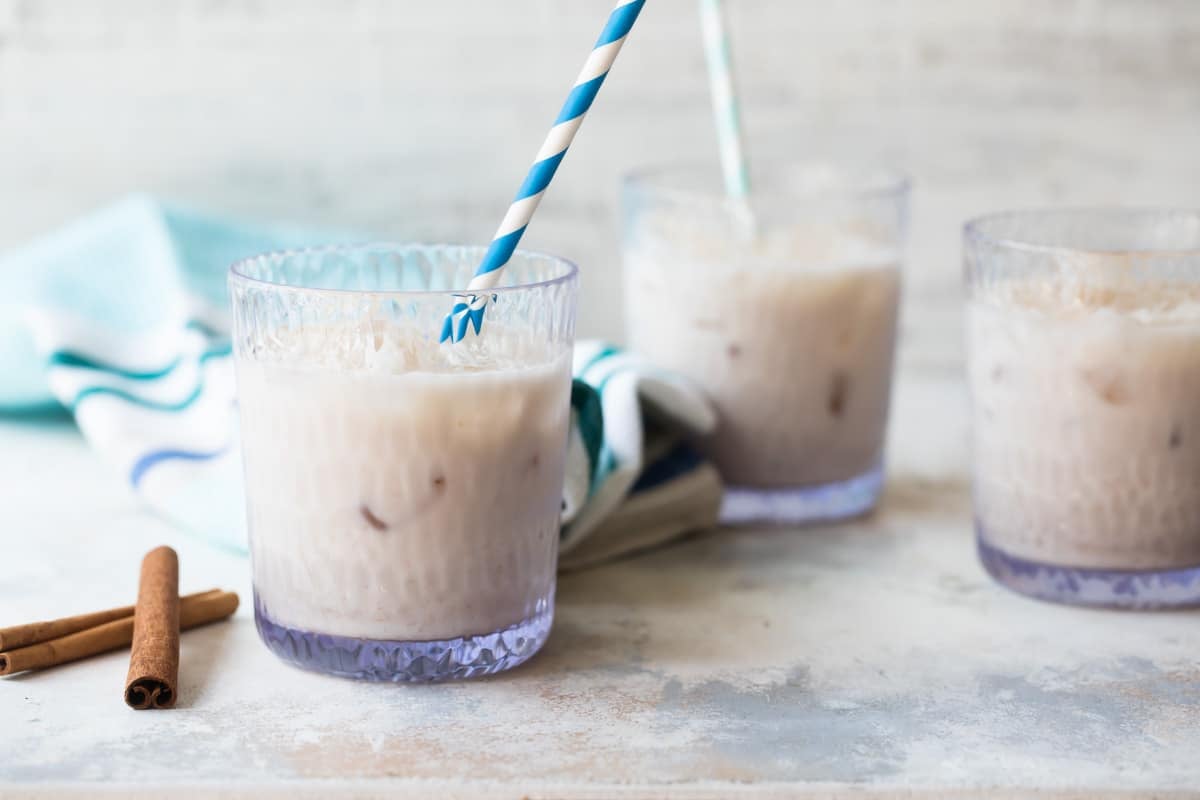 Glasses of cold agua de horchata with blue and white striped straws.