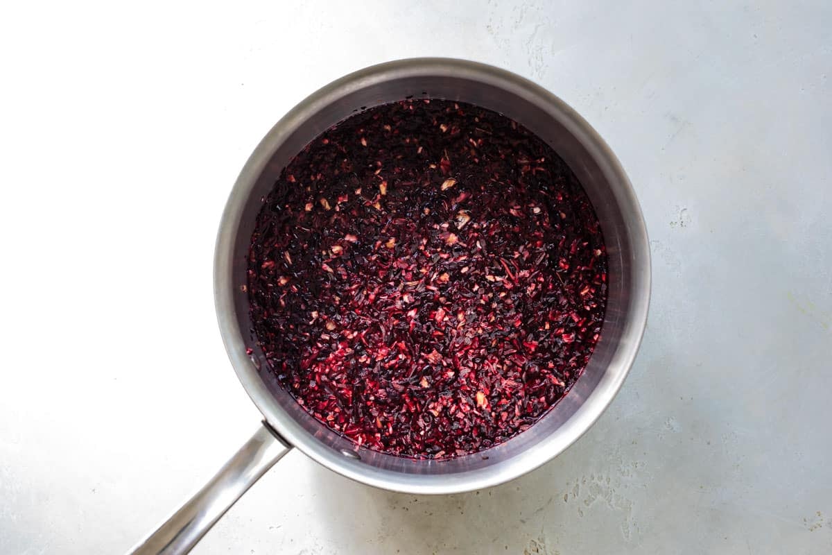 A saucepan with Jamaica (Hibiscus) flowers in it being hydrated in water.