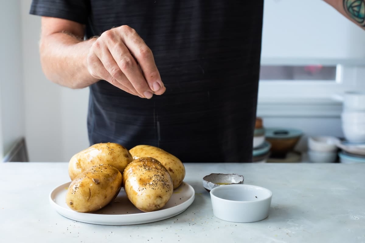 Salting and pepper baked potatoes.