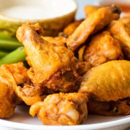 Baked buffalo wings on a white platter.