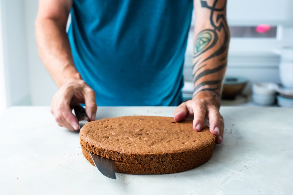 Slicing a chocolate cake in half lengthwise.