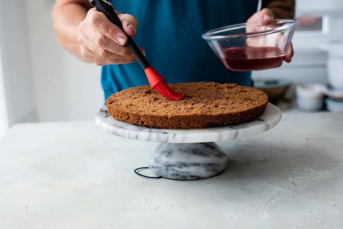 Brushing cherry liqueur on a layer of chocolate cake.