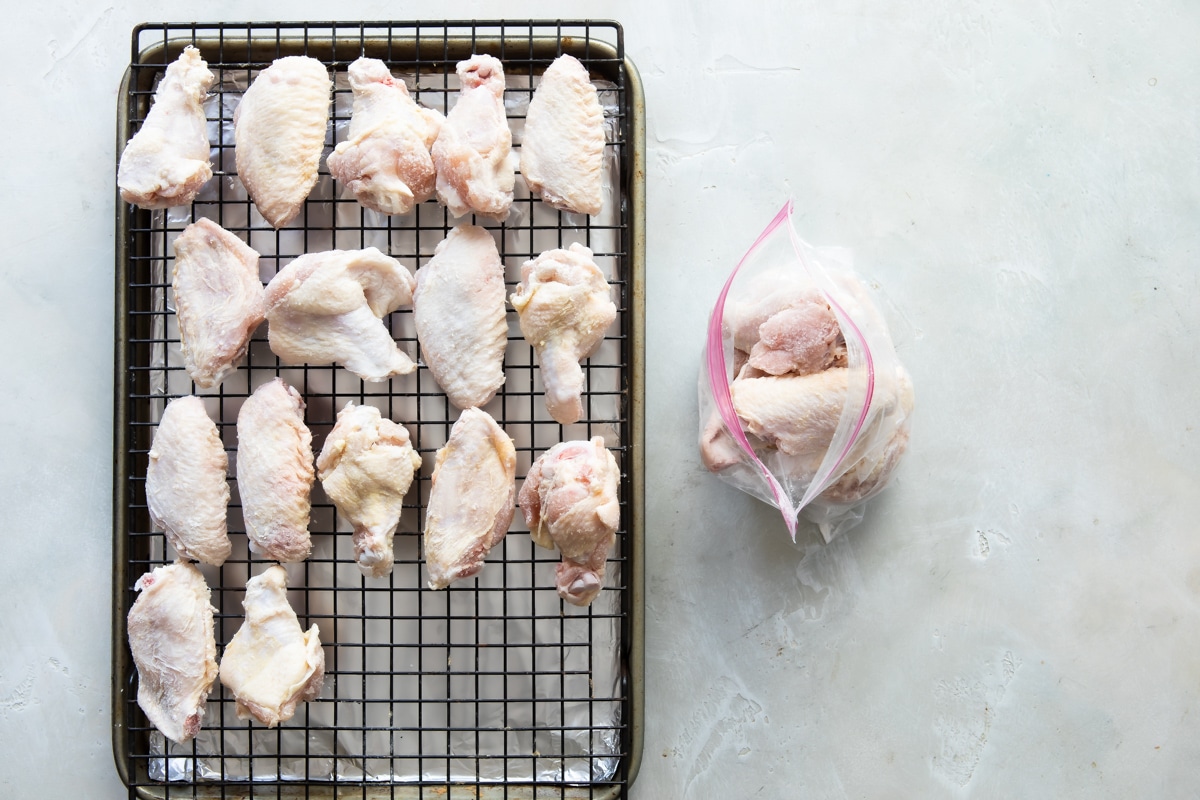Raw wings on a baking rack over an aluminum foil lined baking sheet.