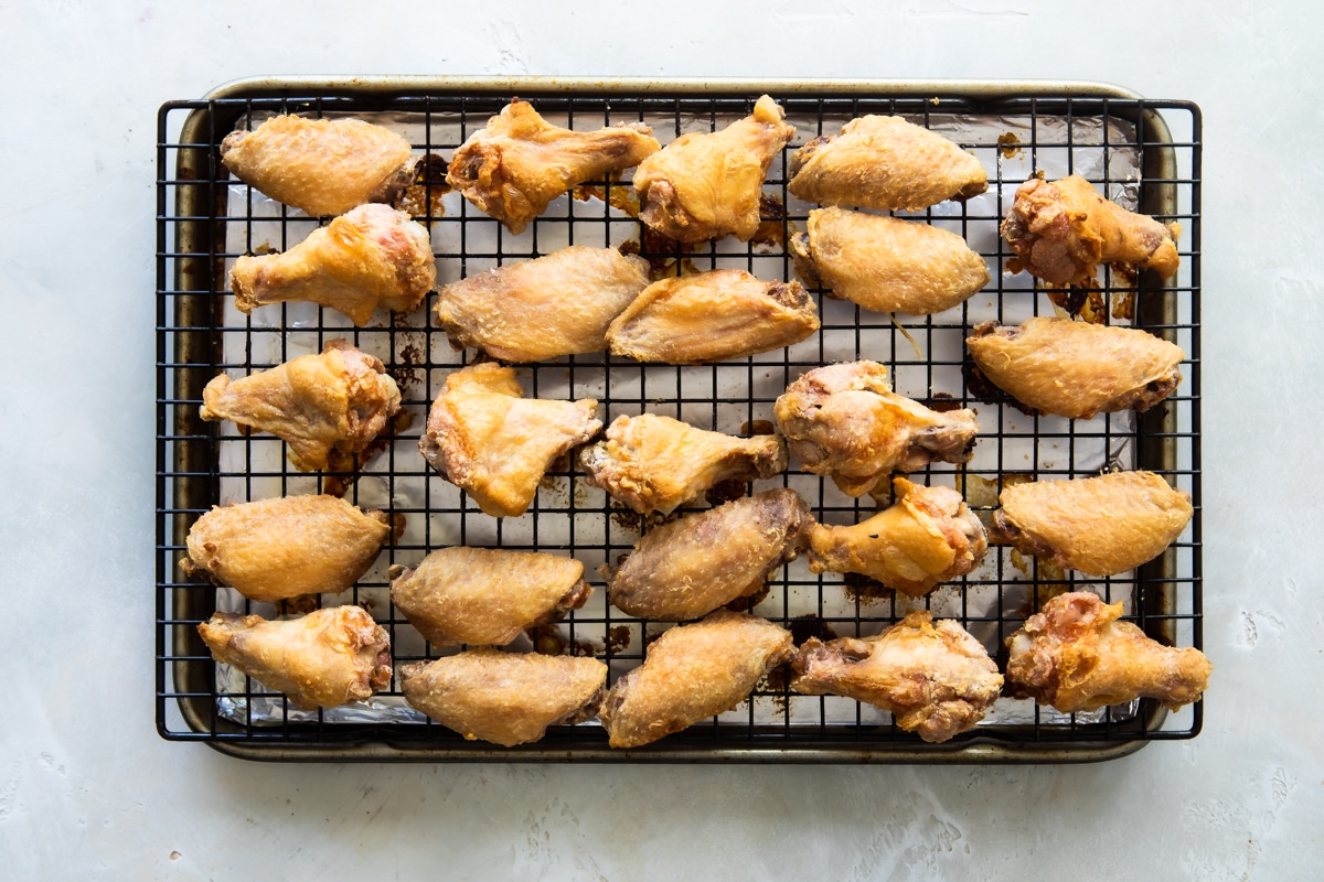 Baked Coca Cola chicken wings on a baking rack over an aluminum foil lined baking sheet.