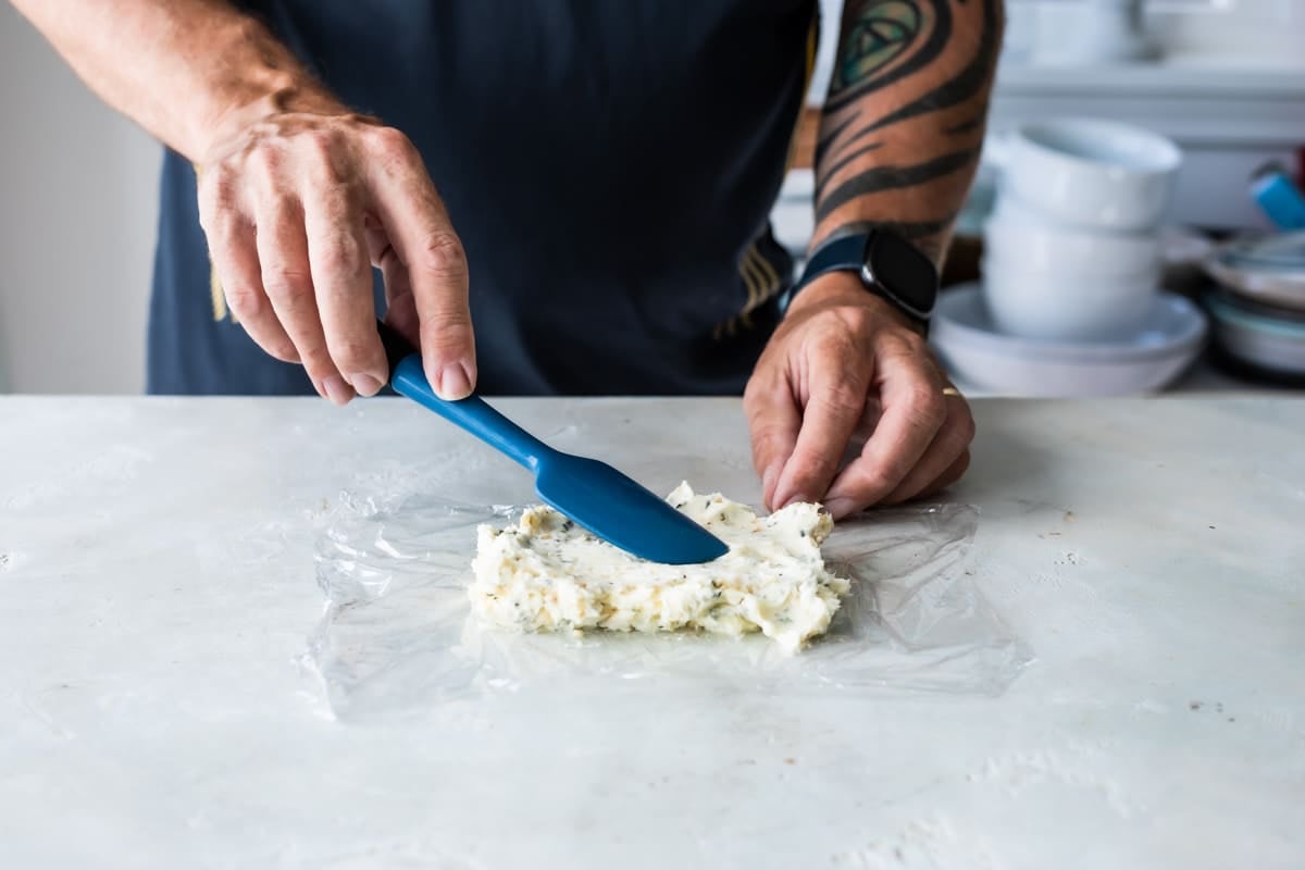 Spreading compound butter in plastic wrap to roll.