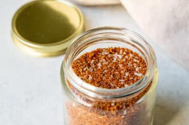 A small glass jar full of dry rub seasoning.