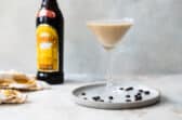 An espresso martini on a plate surrounded by espresso beans.