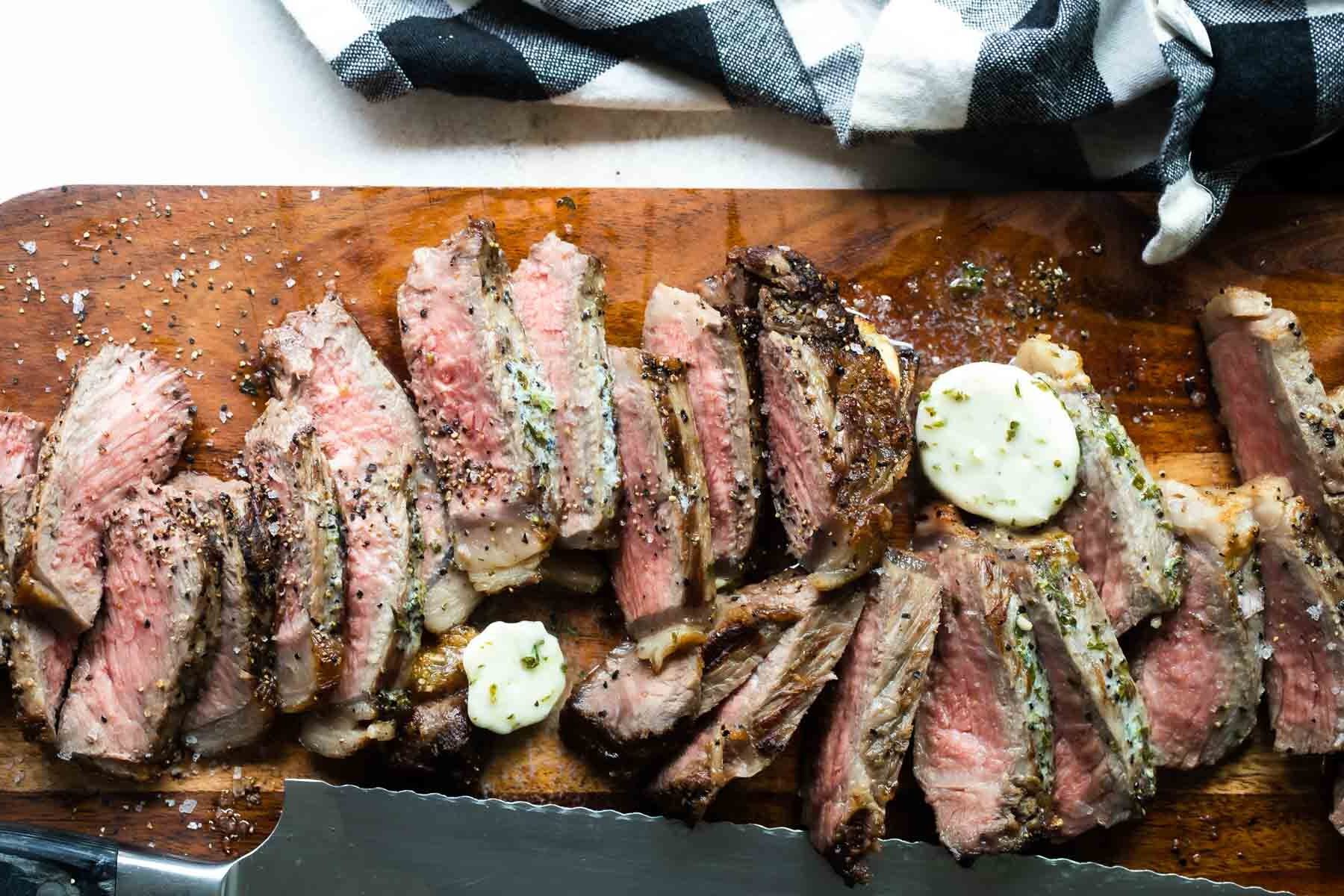 Sliced New York strip steaks on a cutting board.