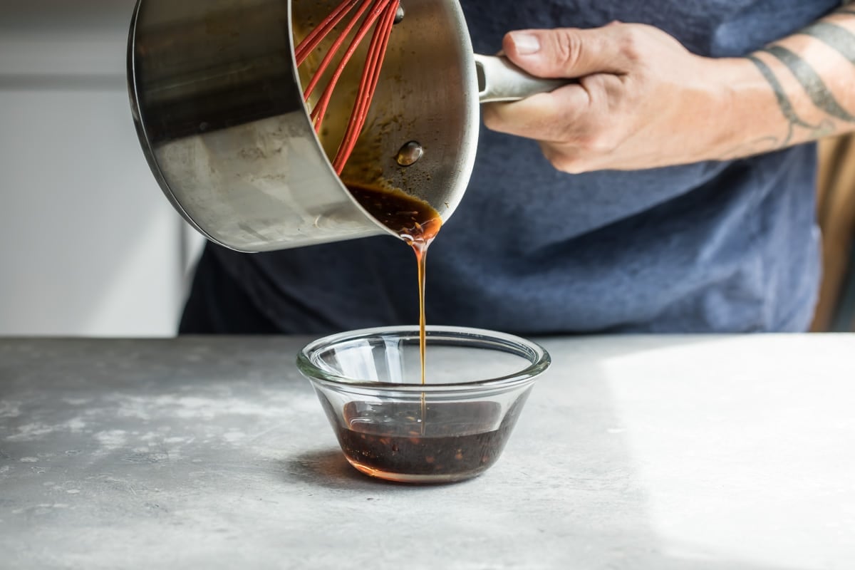 Pouring teriyaki sauce into a bowl to cool.