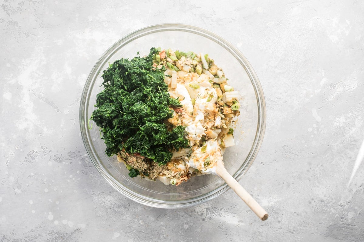 Knorr spinach dip ingredients being mixed together in a clear bowl.
