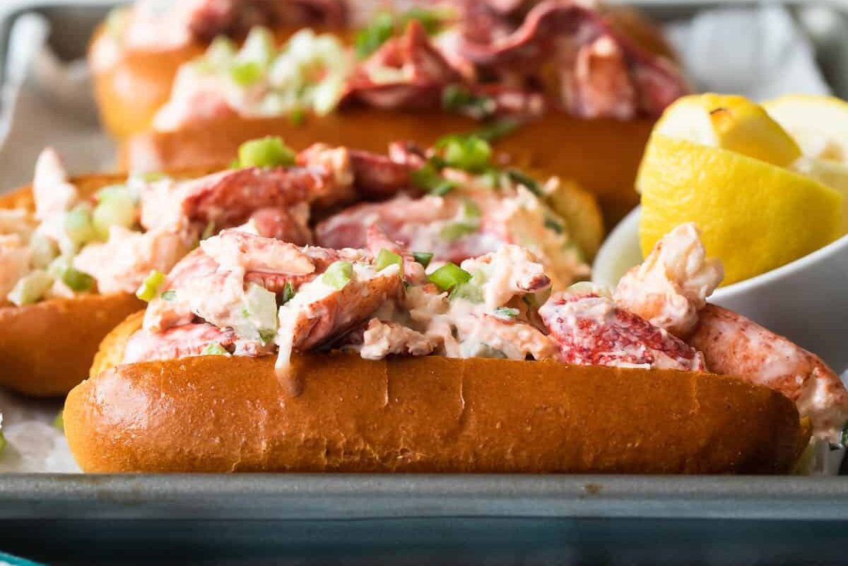 Four lobster rolls on a baking sheet.