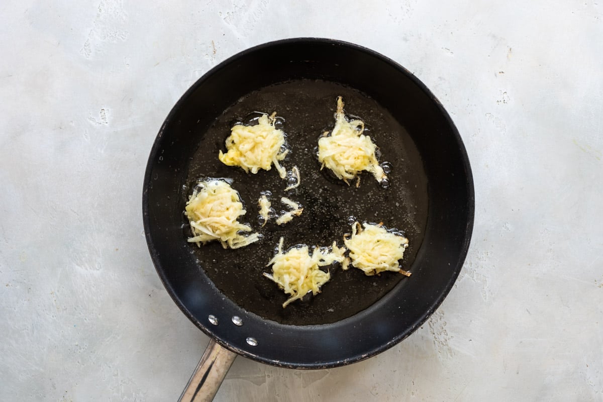 Potato pancakes in a black skillet.