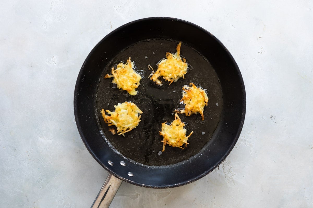 Potato pancakes in a black skillet.