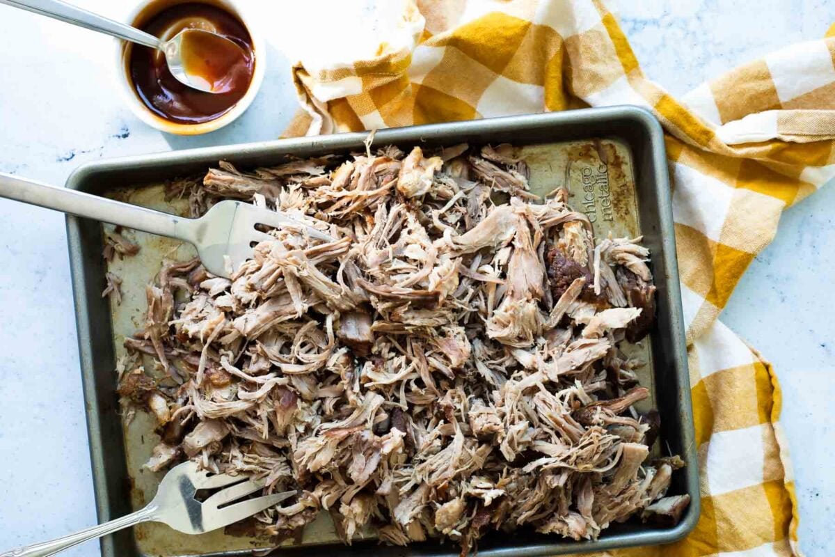 A sheet pan of cooked pulled pork.
