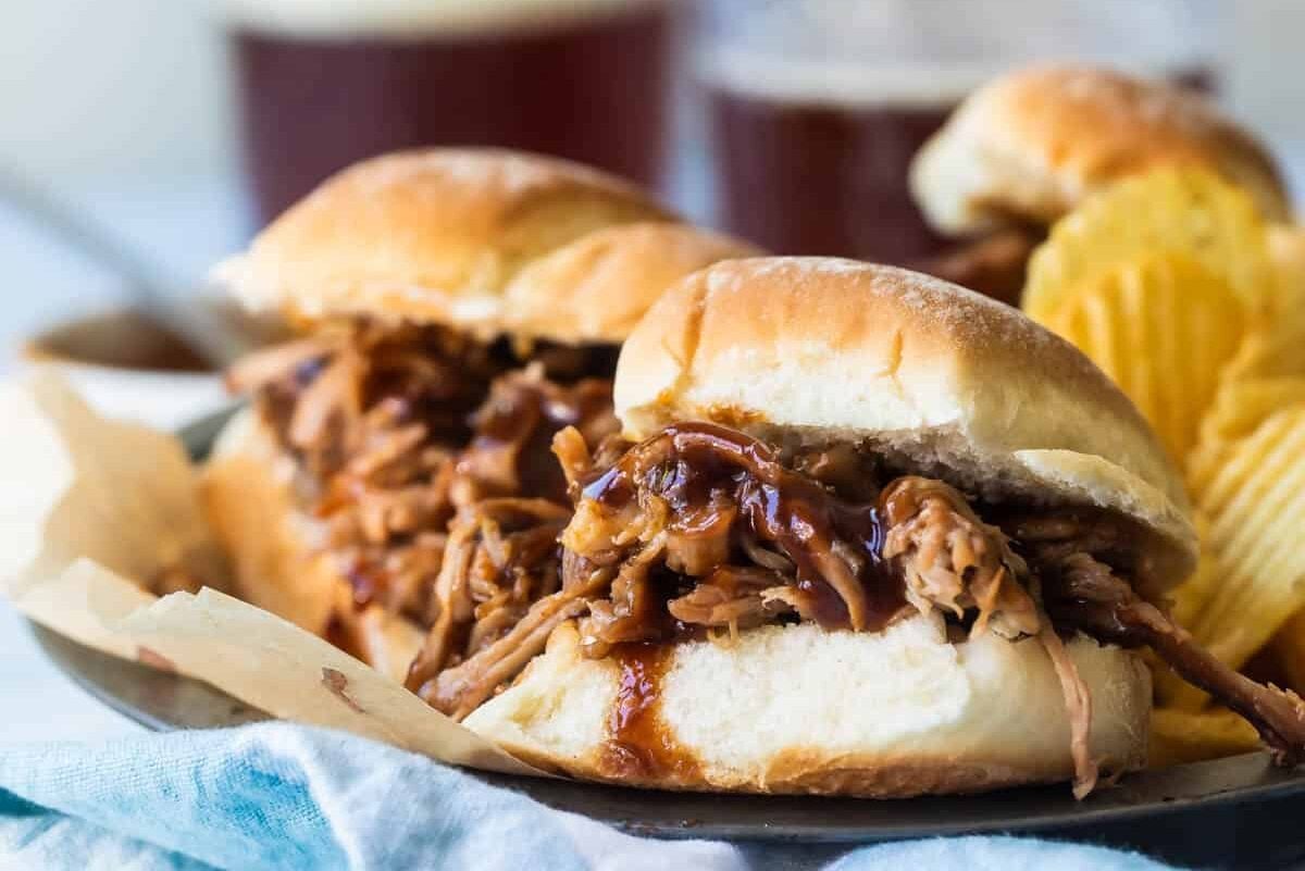 Pulled pork sandwiches with potato chips nearby.