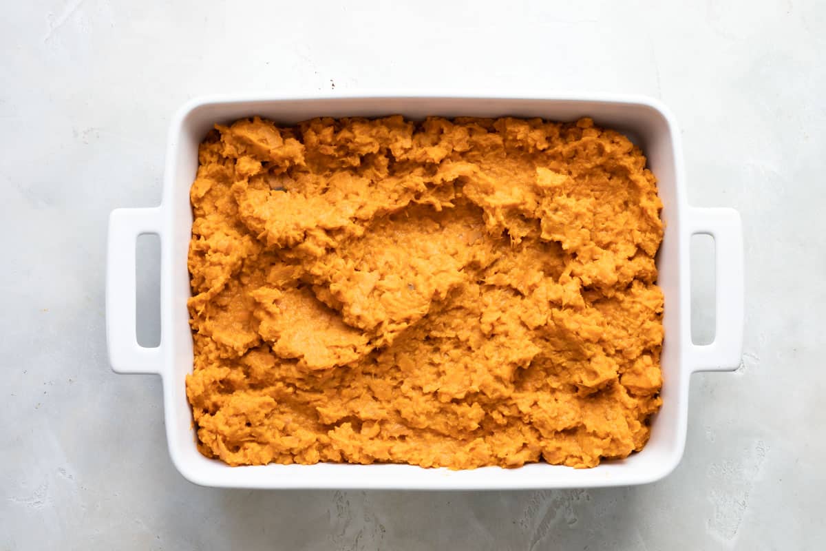 Sweet potato casserole in a white pan before being topped with marshmallows.