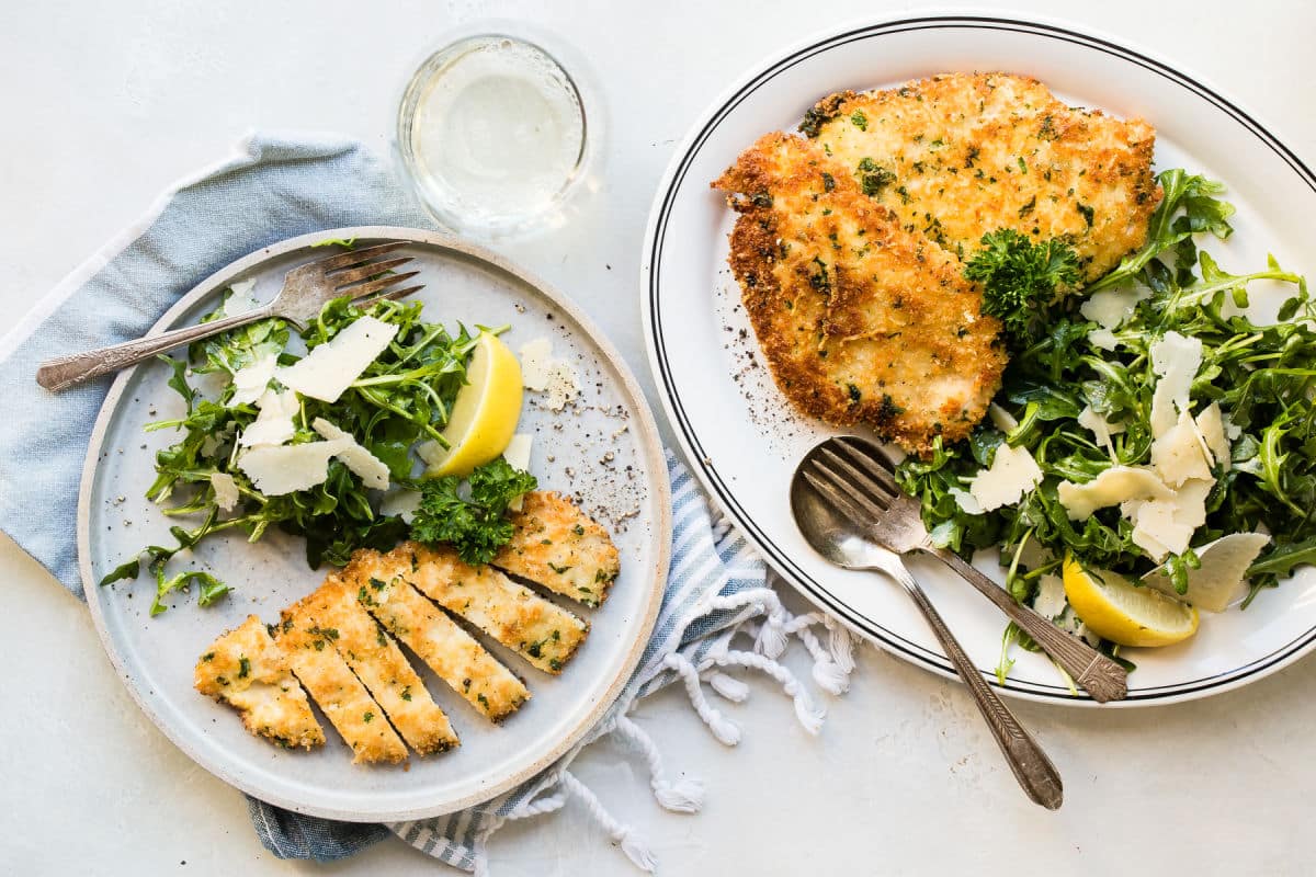 Chicken Milanese on a gray plate with a side of greens.