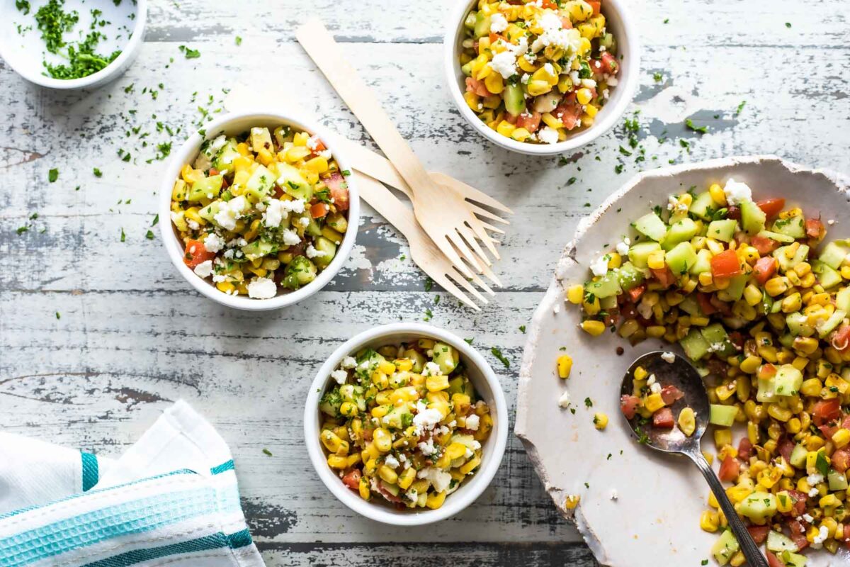 Small white bowls of corn salad with a blue and white napkin nearby.
