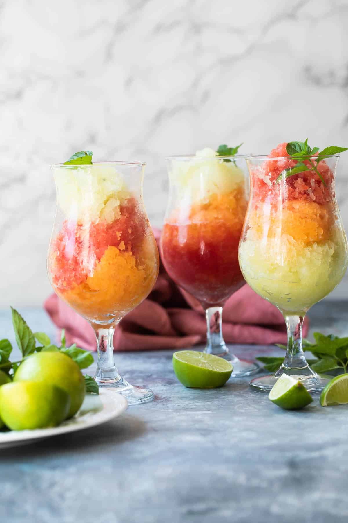 Glasses of cantaloupe, honey dew, and watermelon granita garnished with limes and mint.