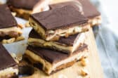 Homemade Snickers bars on a wooden cutting board.