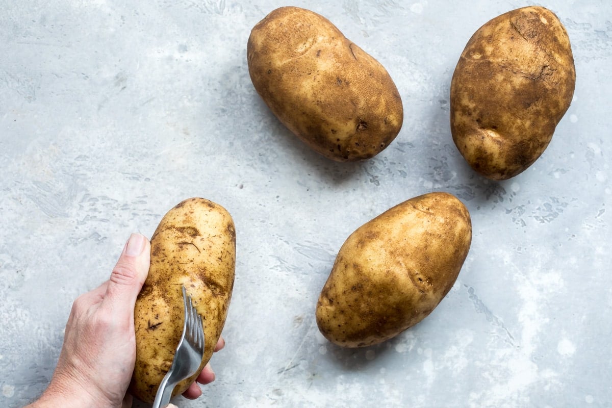 Poking holes in a baked potato with a fork.