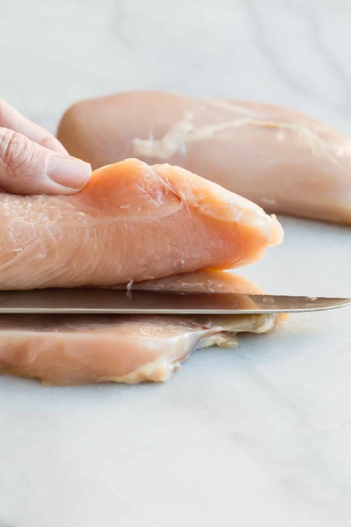 Butterflying a chicken breast in half.